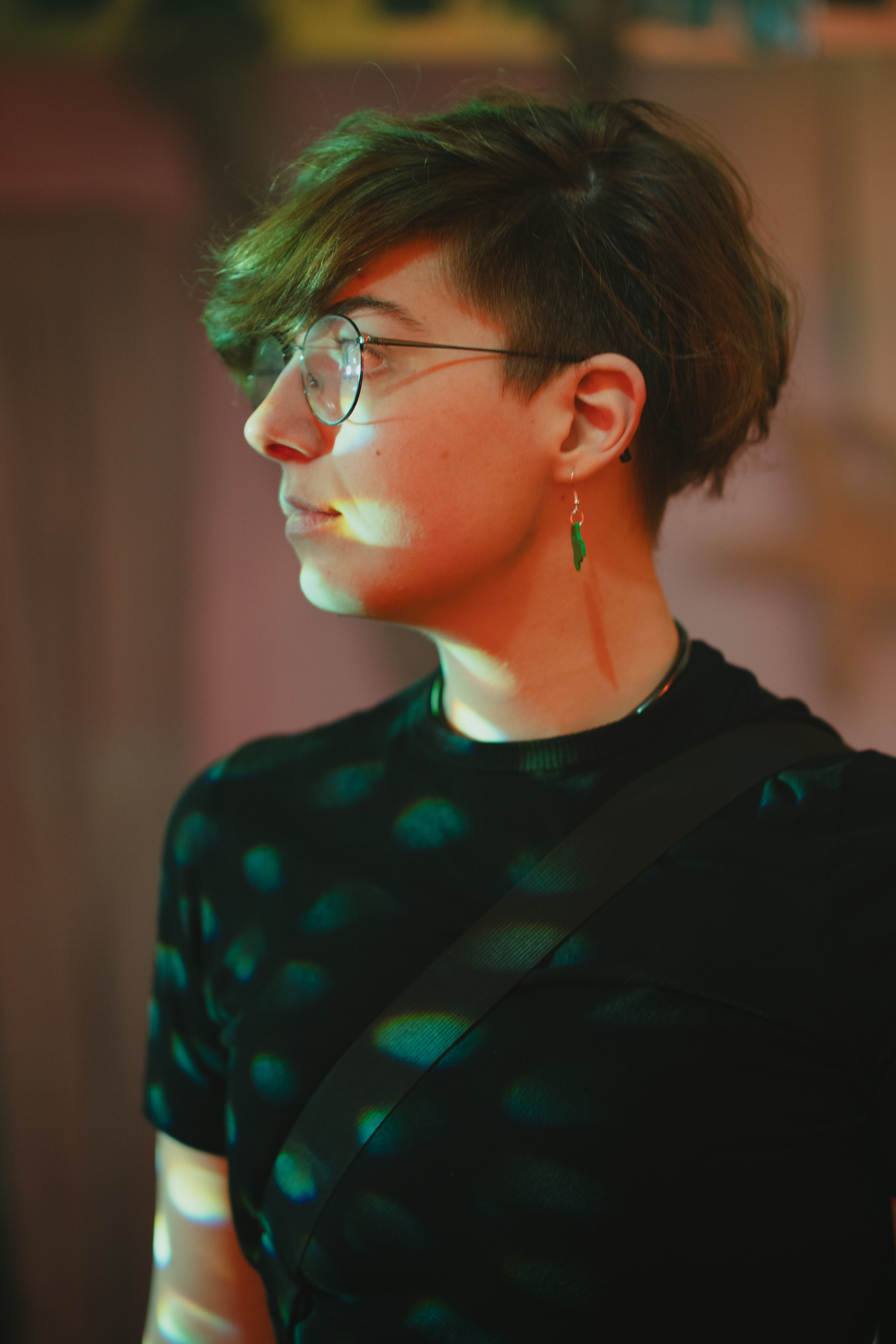portrait photo of a person with round glasses and short brown curls smiling into the camera.